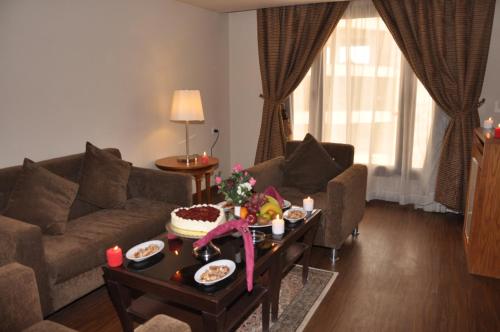 een woonkamer met een bank en een tafel met eten erop bij Reef Al Malaz International Hotel by Al Azmy in Riyad