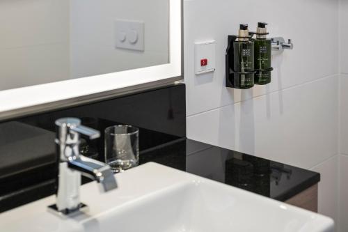a bathroom sink with a faucet next to a mirror at Meliá Frankfurt City in Frankfurt/Main