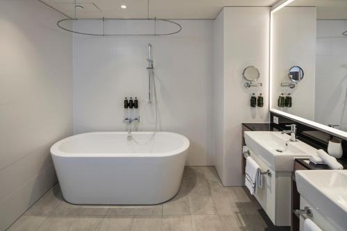 a white bathroom with a tub and two sinks at Meliá Frankfurt City in Frankfurt/Main