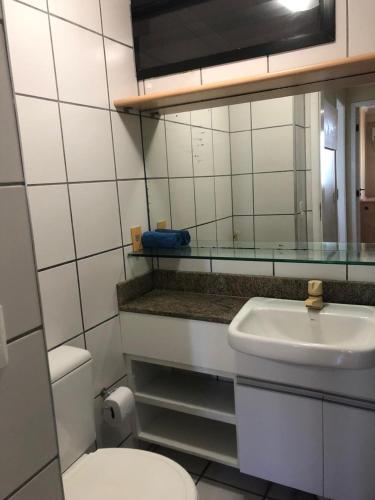 a bathroom with a sink and a toilet and a mirror at Porto de Iracema Residence in Fortaleza