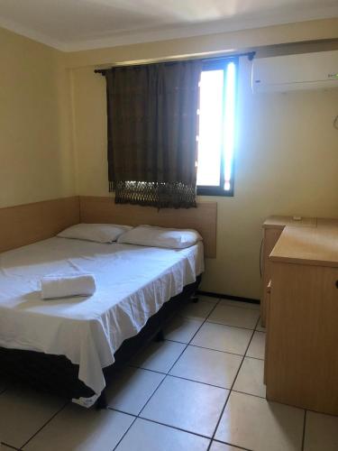 a bedroom with a white bed with a window and a window at Porto de Iracema Residence in Fortaleza