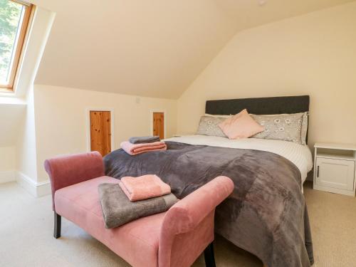 um quarto com uma cama grande e uma cadeira rosa em Nattaden Fourwinds em Okehampton