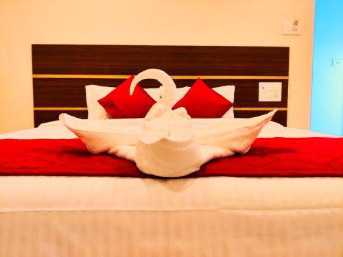 two swans sitting on a bed with red pillows at THAAI RESIDENCY in Tiruvannāmalai