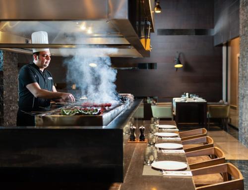 a chef preparing food in a restaurant kitchen at Elexus Hotel Resort & Spa & Casino in Kérynia