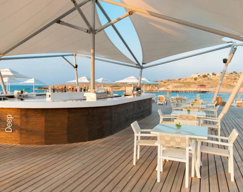 a deck with tables and chairs and a bar at Elexus Hotel Resort & Spa & Casino in Kérynia