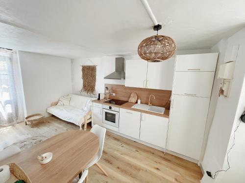 une cuisine avec des armoires blanches et une table en bois dans l'établissement Gîte Chez Gabrielle, au Puy-en-Velay