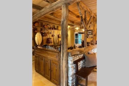- une cuisine avec des placards en bois et un mur en pierre dans l'établissement La Grange. Piscine chauffée, tennis, parc. 15 personnes, à Dégagnac