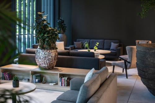 a living room with couches and tables and a potted plant at Meliá Frankfurt City in Frankfurt/Main