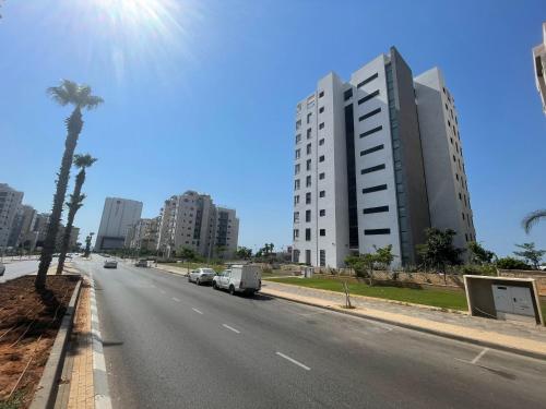 a city street with a building and a palm tree at #דירת יוקרה על הים Sunset Beach Apartment# in Giv‘at Olga