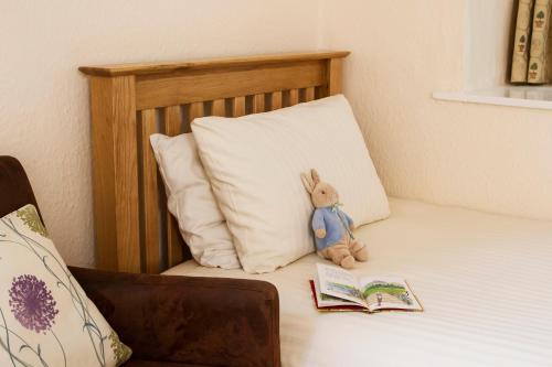 a stuffed rabbit sitting on a bed with a book at Rydal Hall Christian Retreat Centre in Rydal