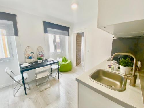 a kitchen with a sink and a table and a counter at BrightHouse Nazaré - Modern Apartments in Nazaré
