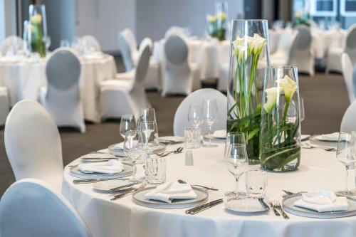 a table with white chairs and a vase of flowers at Meliá Frankfurt City in Frankfurt/Main