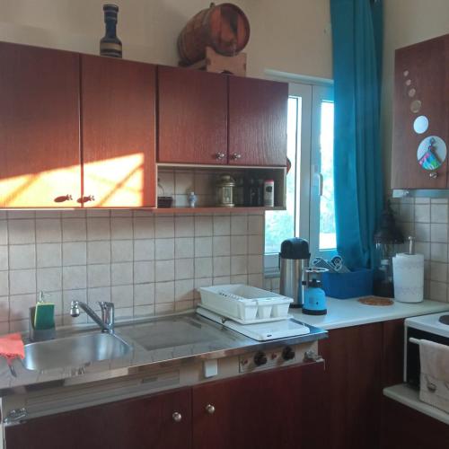 a kitchen with wooden cabinets and a sink and a window at Casa D'armaros in Kissamos