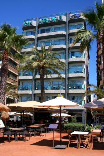 a hotel with tables and umbrellas and palm trees at Hotel Miramar in Lloret de Mar