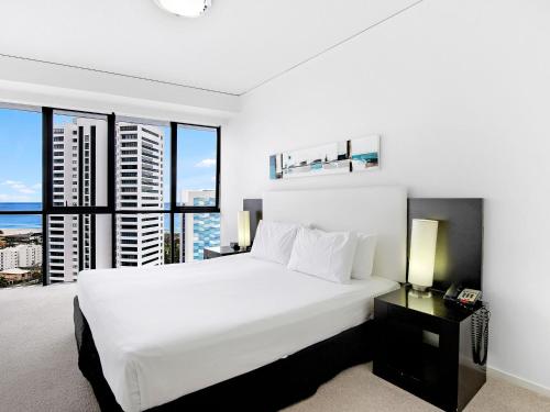 - une chambre avec un grand lit blanc et de grandes fenêtres dans l'établissement Beautiful Ocean View High Floor 3 Bedroom Apartment at Sierra Grand, à Gold Coast