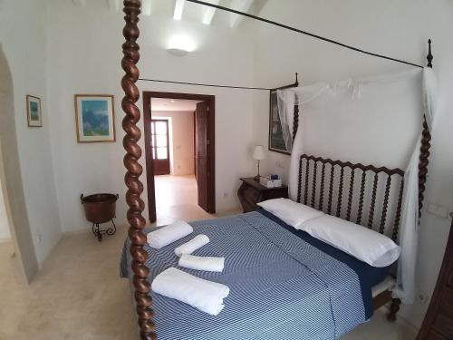 1 dormitorio con cama con dosel y almohadas blancas en CAL SENYOR DAMIÀ, en Santanyí
