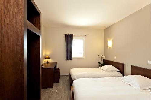 a hotel room with two beds and a window at Le Ya'Tis in Saint-Laurent-des-Arbres