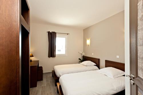 a hotel room with two beds and a window at Le Ya'Tis in Saint-Laurent-des-Arbres