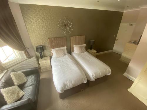 a bedroom with two beds and a couch at Ashmira Guest House in Weymouth