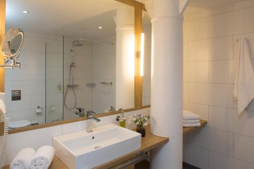 a white bathroom with a sink and a mirror at Weberei Bendix Hotel & Appartements in Dülmen