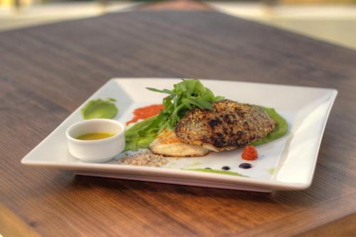 a white plate with a meat dish and a sauce at Ntinas Filoxenia Hotel & Spa in Skala Potamias