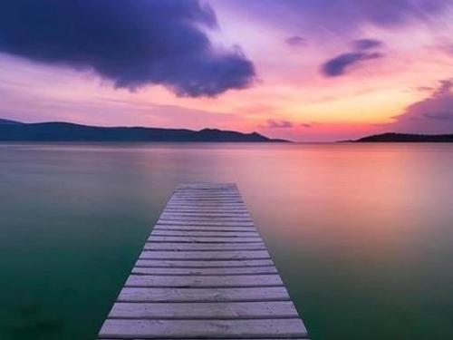 a wooden dock in the middle of a body of water at Klima Paradise in Klíma