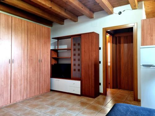 una cucina con armadi in legno e una TV di ANTICA CORTE ORTAIA APPARTAMENTI a Povegliano Veronese