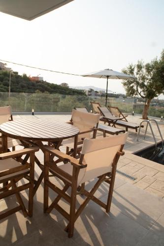 a wooden table and chairs with an umbrella on a patio at Hello Village Chania in SFakianalíon