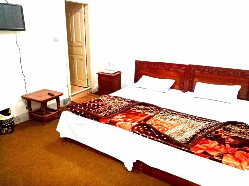 a bedroom with two beds with white sheets at Hotel Tour De Swat in Swat