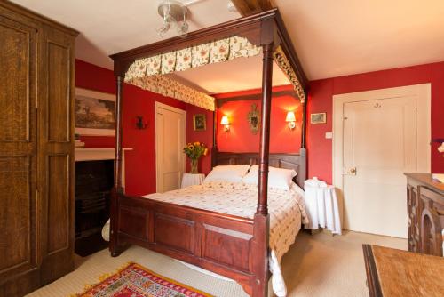 een slaapkamer met een hemelbed met rode muren bij St Annes Bed and Breakfast in Painswick
