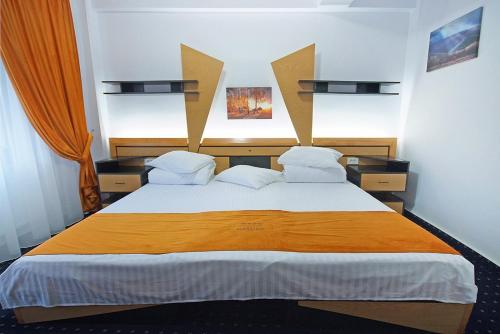 a bedroom with a large bed with an orange blanket at COMPLEX PANORAMIC in Slănic-Moldova