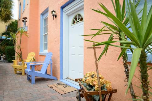 a house with two blue chairs and a white door at Old Colorado Inn in Stuart