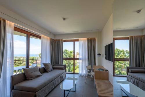a living room with a couch and large windows at Sicilia's Art Hotel & Spa in Acitrezza