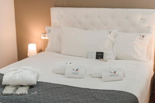 a white bed with white pillows and towels on it at Sicilia's Art Hotel & Spa in Acitrezza