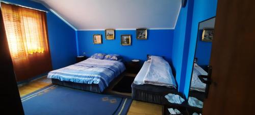 a blue bedroom with two beds and a window at Sobe Seka in Golubac