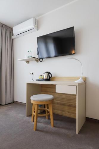 a desk with a stool and a tv on a wall at Poznań West Hotel - Airport in Poznań