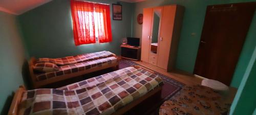 a bedroom with two beds and a window and a mirror at Sobe Seka in Golubac