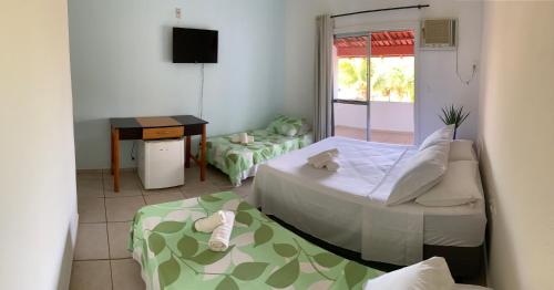 a room with two beds and a table and a television at Vivenda Xawã in Corumbau