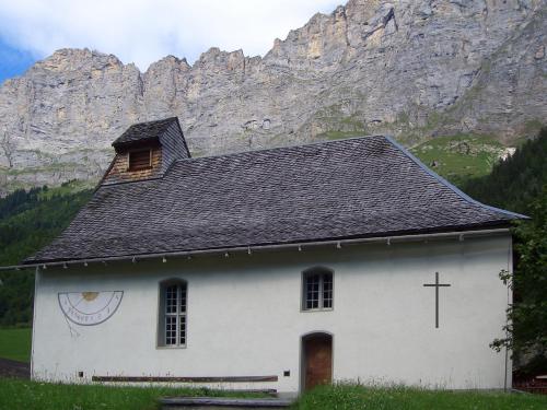 a white church with a mountain in the background at Triftblick in Gadmen