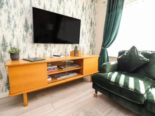 a living room with a television on a wooden entertainment center at 2 Pine Grove in Preston