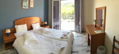 a bedroom with two beds and a table and a window at Nafsika Hotel in Agios Stefanos