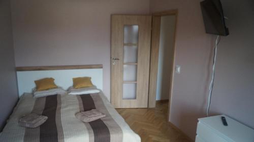 a bedroom with two beds with yellow pillows and a television at Old Town Chic - 2 pokoje, klima, bezpłatny parking, F-VAT in Wrocław