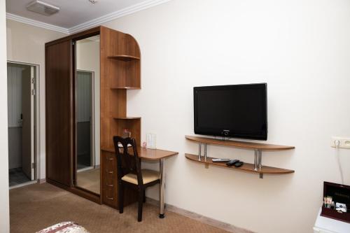um quarto com uma televisão e uma secretária com uma cadeira em Persian Palace Hotel em Kiev