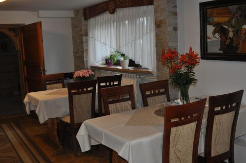 a dining room with tables and chairs with flowers on them at Pokoje u Marysi in Leśnica