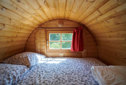- une chambre avec un lit dans une pièce en bois dotée d'une fenêtre dans l'établissement Les Tonneaux Bourguignons du Carré Saint Pierre, à Marey-lès-Fussey