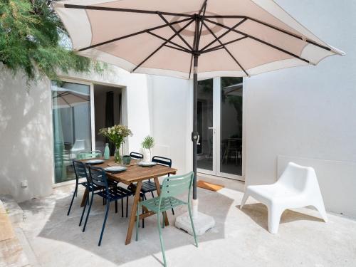 une table en bois avec des chaises et un parasol dans l'établissement La Cala Malmousque - Magnifique petite maison au bord de l'eau, à Marseille
