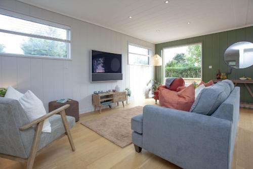 a living room with two blue chairs and a tv at The Willows, Strawberryfield Park in Cheddar