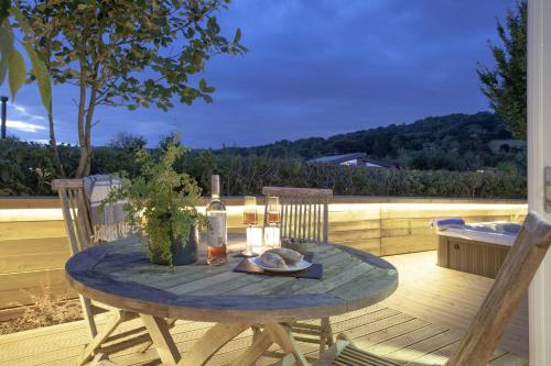 a table with a bottle of wine and two chairs on a deck at The Willows, Strawberryfield Park in Cheddar