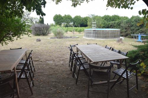 two wooden tables and chairs in a yard at Villa de l'Agapé - Drome provencale - 7 ch - 10 à 24 personnes - 350m2 in Tulette