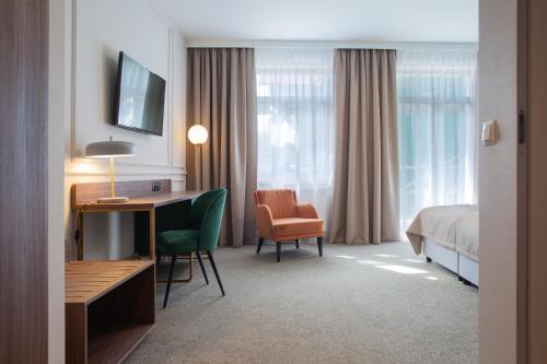 a hotel room with a bed and a desk and a chair at Hotel Willa Tatrzańska in Krynica Zdrój